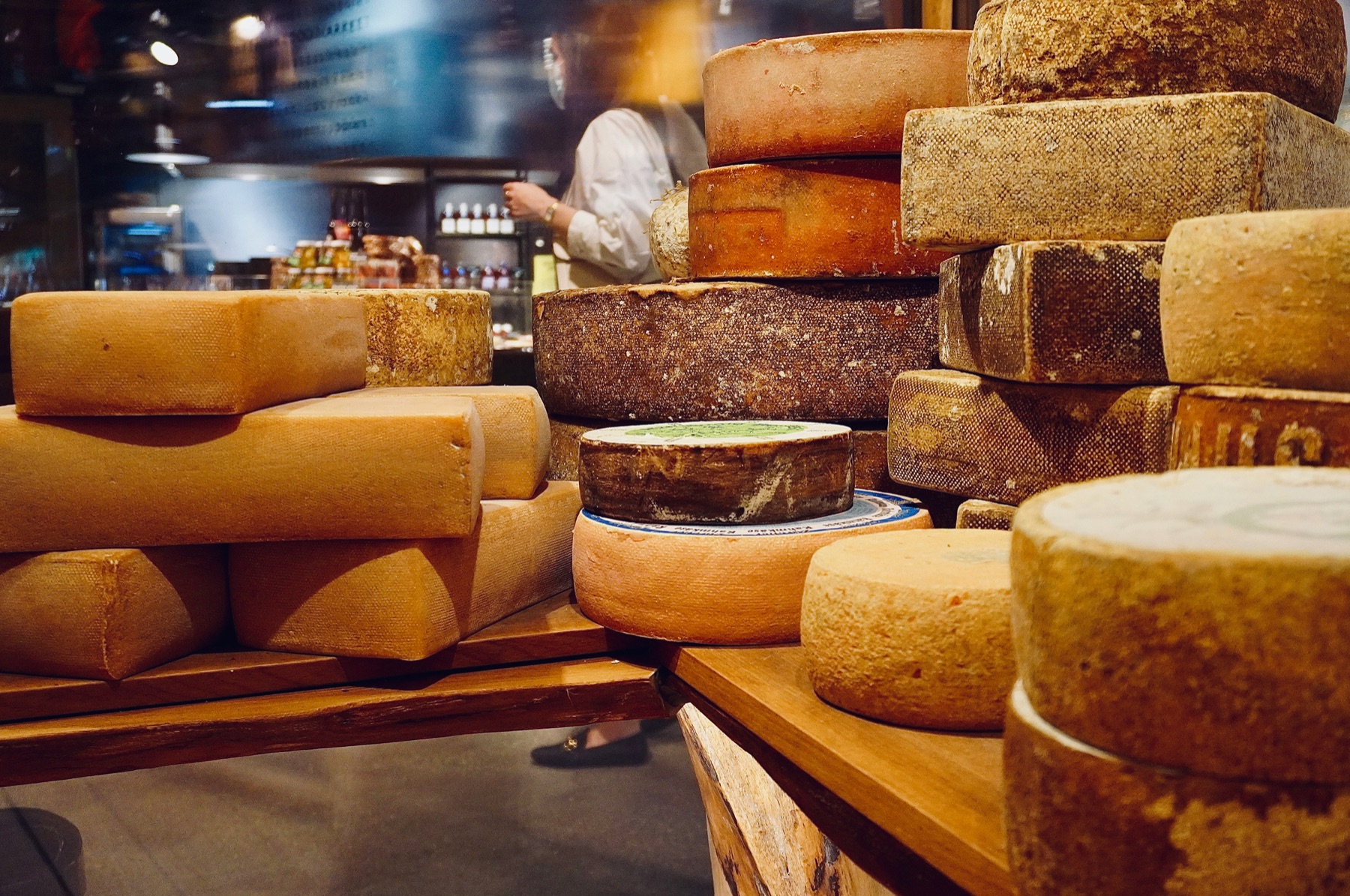 Wheels of artisanal cheese stacked on the wooden shelves of a traditional cheesemonger