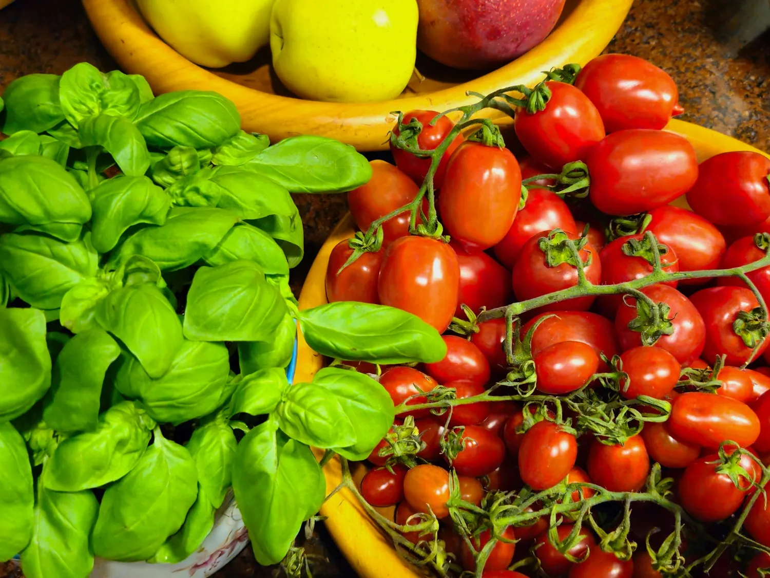 Fresh basil and vine-ripened tomatoes with seasonal fruit in rustic bowls at Rosmarino, Indiranagar